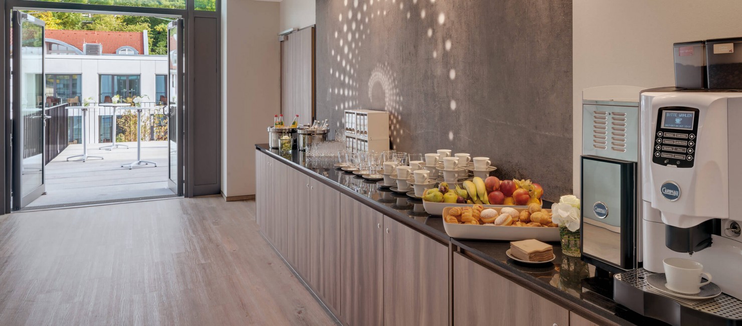Theke mit Kaffeeautomat, Obst- und Gebäckschale